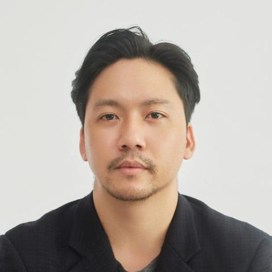 Portrait of a business man sitting thoughtfully at a desk in a bright, minimalist setting.